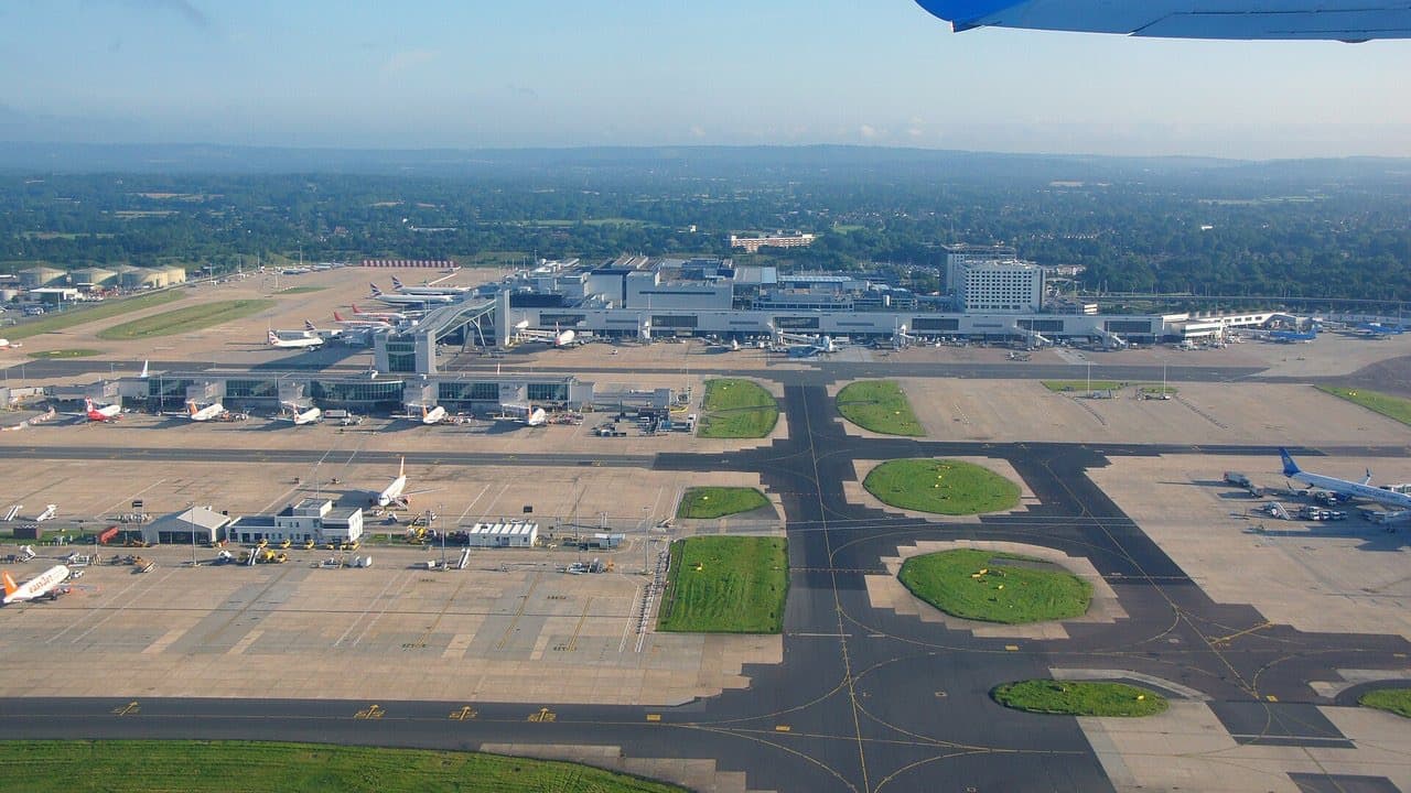 Aerial view of Gatwick Airport with aircraft parked at the terminal piers and runways across the foreground