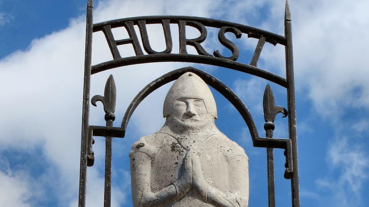 The Hurstpierpoint village sign showing a stone knight with hands in prayer under the word HURST