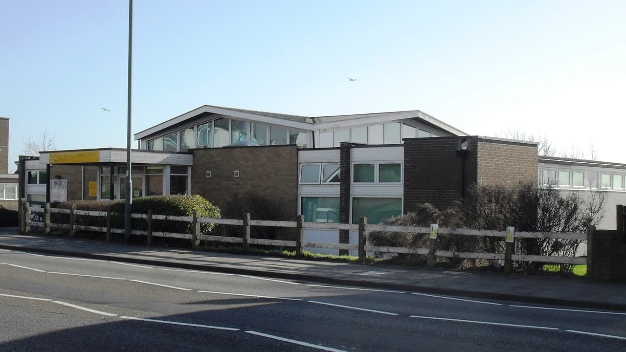 Portslade Library, a low brick and glass building beside the A270 Old Shoreham Road under a clear sky