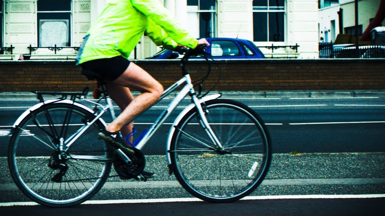Cyclist in a bright yellow hi-vis jacket riding a bike along a Brighton and Hove road
