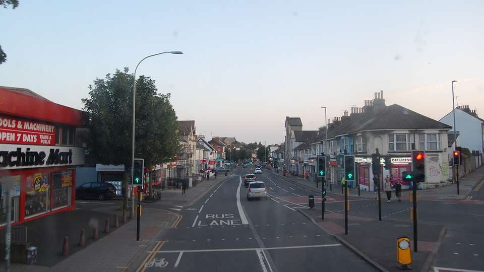 Lewes Road in Brighton looking south, with a bus lane, traffic lights and shops and houses on both sides