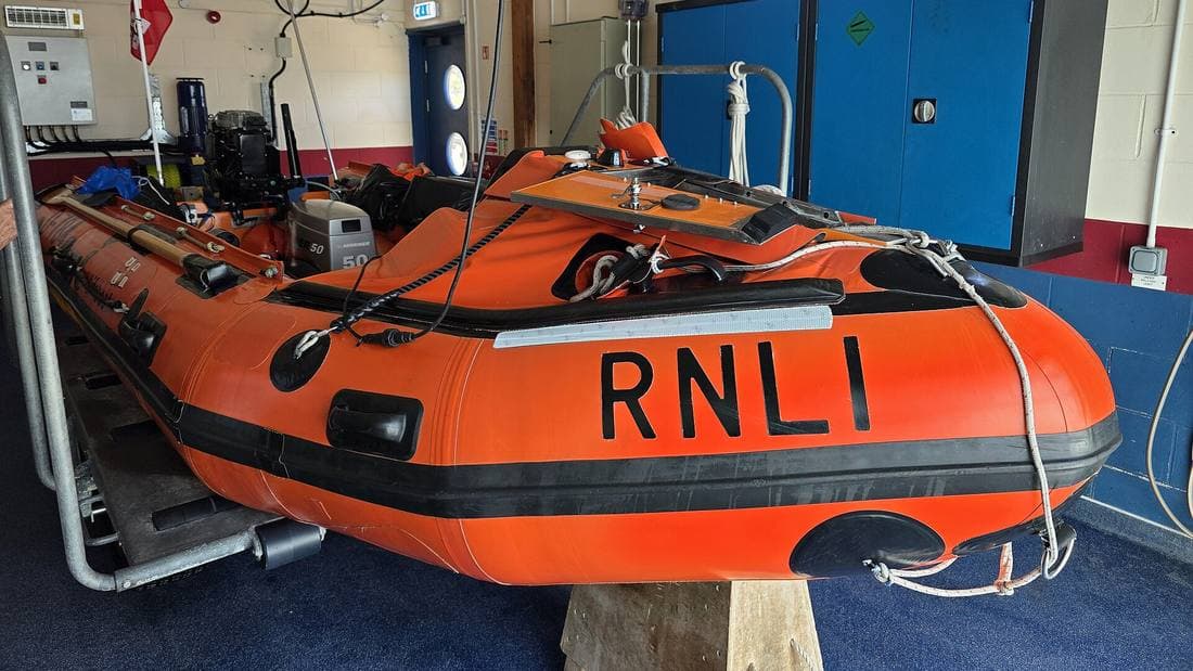 An orange RNLI inshore lifeboat on its launching carriage inside the Shoreham Harbour lifeboat station