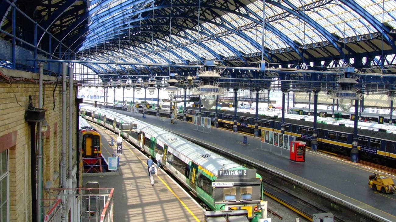 A green Southern train standing at a platform under the large curved glass and iron roof of Brighton station