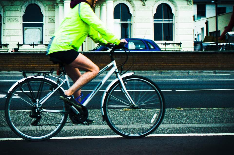 Cyclist in a bright yellow hi-vis jacket riding a bike along a Brighton and Hove road