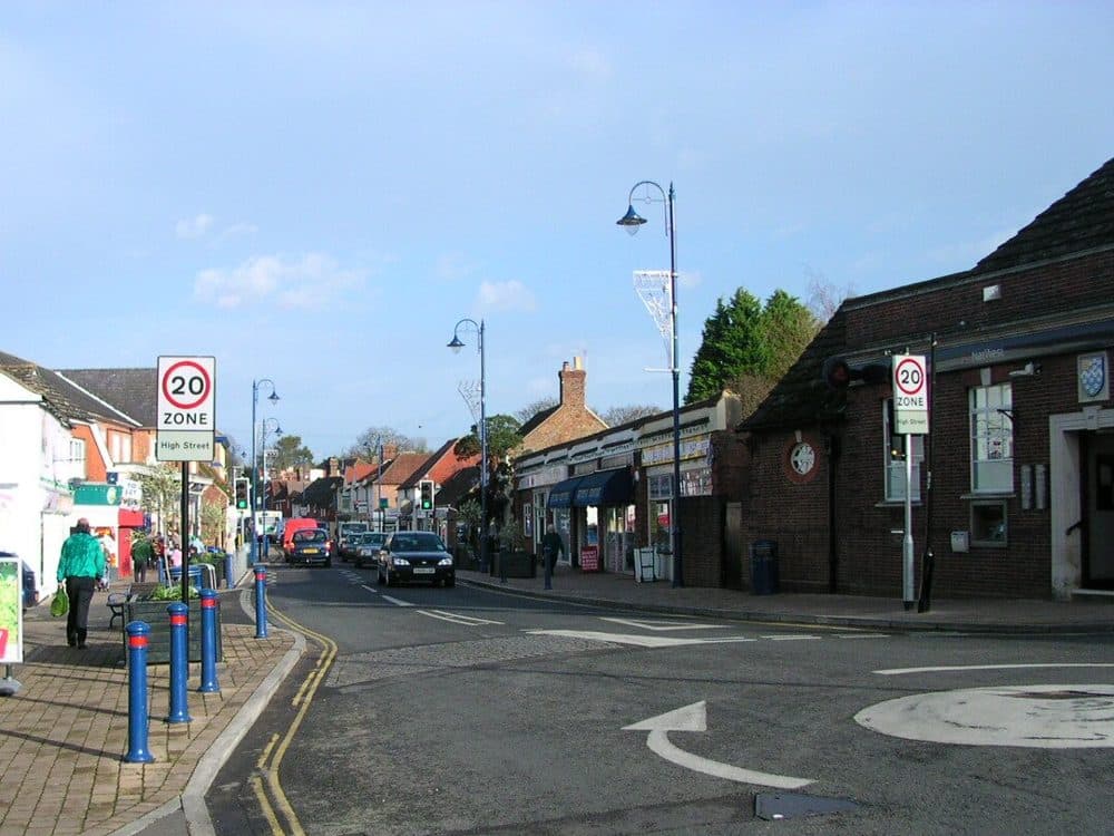 Billingshurst High Street in West Sussex, with shops on the left, a brick building on the right and a blue sky above
