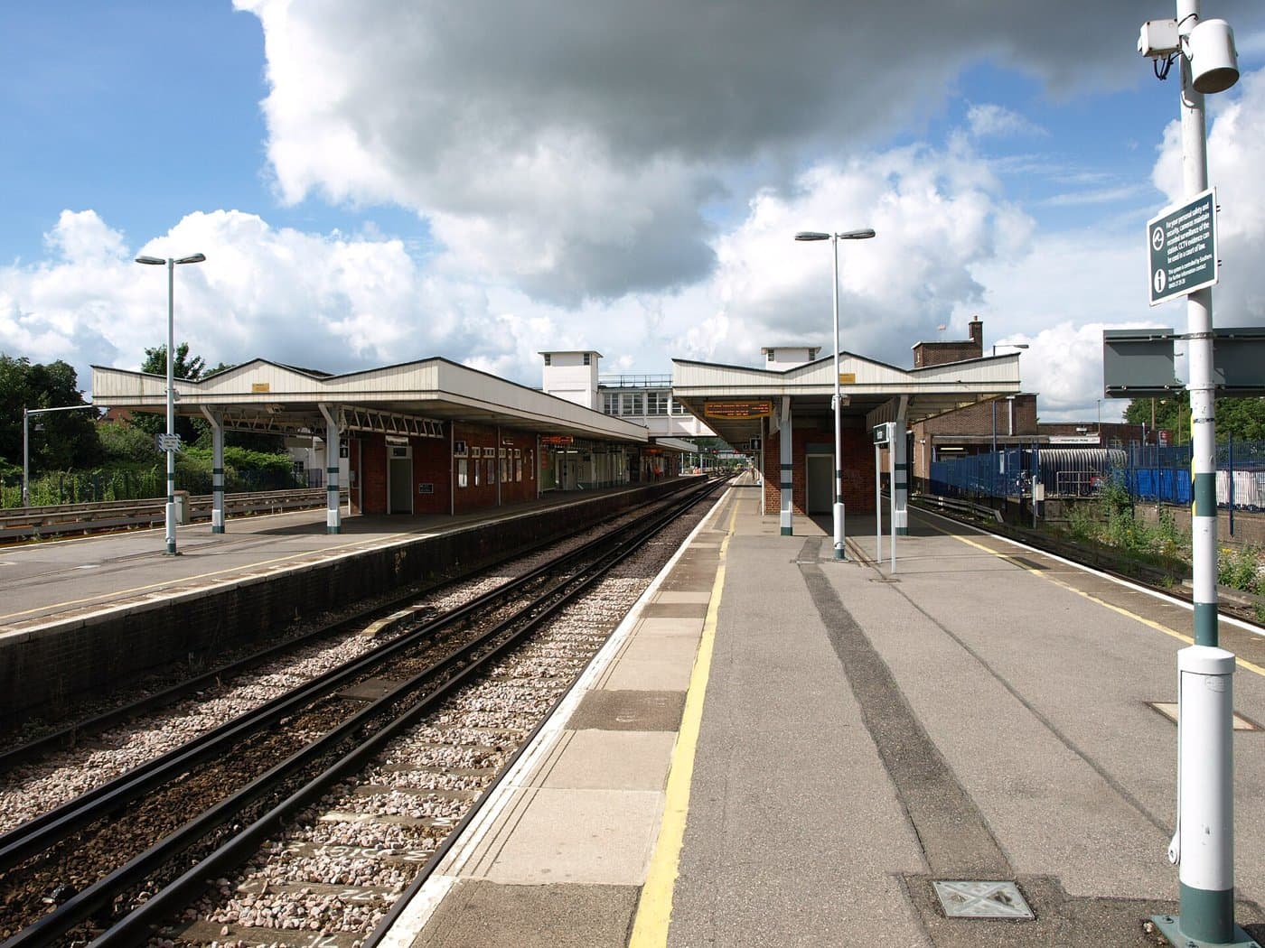 An empty platform at Horsham railway station with covered waiting areas and railway tracks beside it