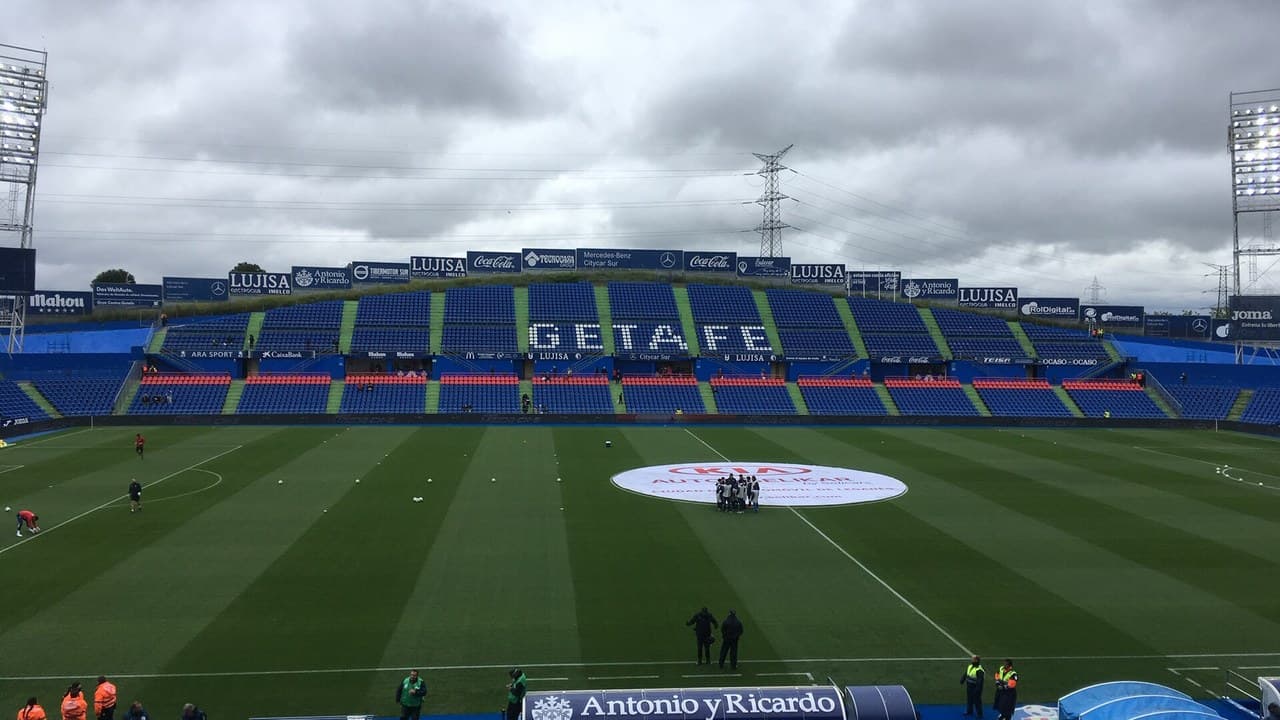 The Coliseum stadium in Getafe, Spain, with the pitch, the blue stands and floodlights under a cloudy sky