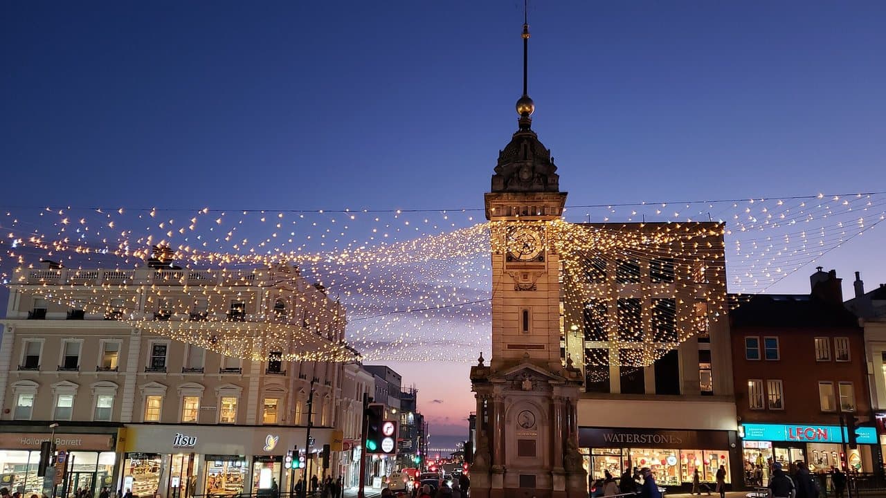 Brighton's Clock Tower at dusk with festive lights strung across the street